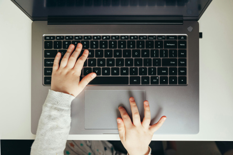 A child's hands typing on a laptop