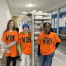 Photo shows three student ambassadors in orange shirts standing in front of a lunch cart at West Bedford School.